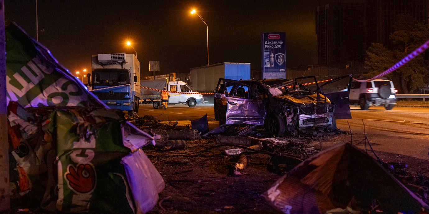 Räddningspersonal röjer bråte och skadad väginfrastruktur intill en förstörd bil efter en rysk attack mot Kyjiv under natten mot tisdagen.