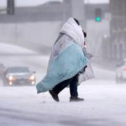 En person invirad i ett duntäcke går över en snötäckt gata i St Louis i Missouri. 