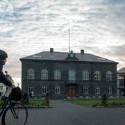 En kvinna cyklar förbi Alltinget i Reykjavik