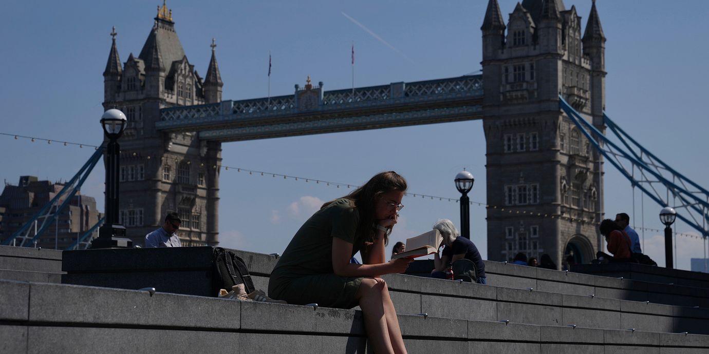 En kvinna sitter framför Tower Bridge i London.