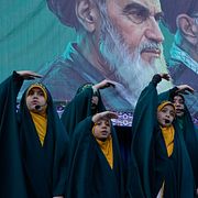 En flickkör uppträder i Teheran i slutet av april för att uppmärksamma imam Rezas födelsedag. Med händerna gör de en rörelse som ska visa hur robotar flyger över himlen, enligt AP:s fotograf. 