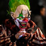 En man utklädd till en läskig clown tittar på sin telefon under ett Halloweenfirande i tyska Essen.