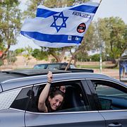 En kvinna viftar med en israelisk flagga från ett bilfönster under valdagen i Tel Aviv på tisdagen.