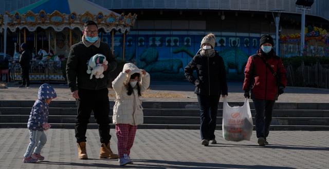 Kinesisk familj i munskydd. Andy Wong / AP