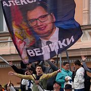 Anhängare till Serbiens president Aleksandar Vucic håller upp en flagga med hans porträtt under ett valmöte i Novi Sad på fredagen.