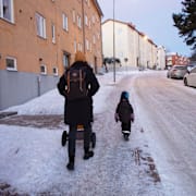 Mamma och barn med barnvagn på snöig trottoar på vintern, Hägersten.