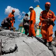 Räddningstjänst söker överlevande under en moské som har rasat i Pemenang, Lombok. 