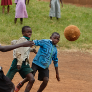 Skolbarn leker i Uganda, ett av länderna Sverige ger bistånd till. Till höger biståndsminister Johan Forssell (M).