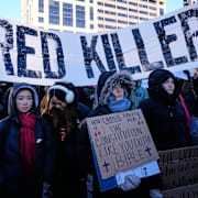 Människor samlas under en banderoll med texten ”inhyrda mördare”, ett kritiskt budskap riktat mot migrationspolisen ICE.