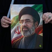 En kvinna håller Mojtaba Khameneis porträtt.