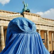 Arkivbild på en kvinna i burka Brandenburger tor i Berlin.