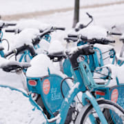 Elsparkcyklar i snö till vänster. Till höger en skärmdump av SMHI:s varningskarta. 