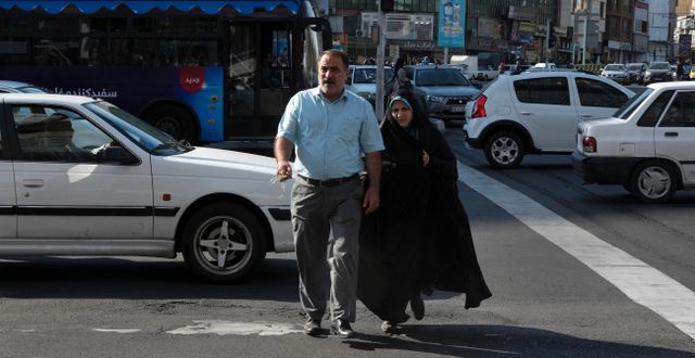 En kvinna och en man korsar en gata i Teheran, 14 november. Vahid Salemi / AP