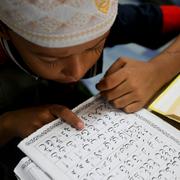 Ett barn från rohingyafolket läser koranen. Även Hanifi Rohingya-skriften, som baseras på det arabiska alfabetet, ligger också i farozonen. Men nu pågår projekt för att rädda språket.