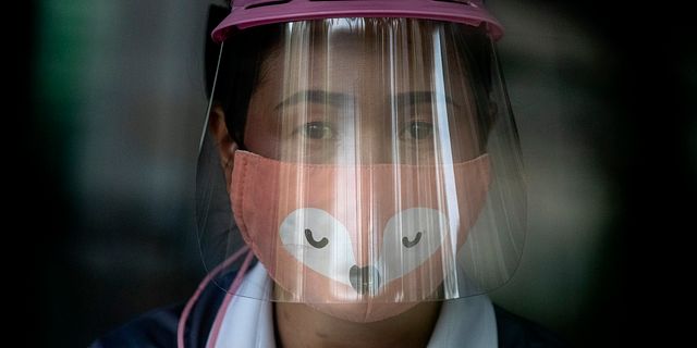 Kvinna med munskydd och visir i Thailand. Gemunu Amarasinghe / TT NYHETSBYRÅN