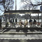 Människor sitter i vårsolen på en uteservering på Strandvägen i vårväder med sol och plusgrader.