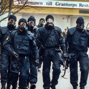 Poliser från nationella insatsstyrkan utrustade med gasmask och automatkarbin går i samlad trupp på en gata i Stockholmsförorten Flemingsberg 4:e december 1994, i samband med jakten på förövarna till massakern på Stureplan/ambulanspersonal på plats efter skjutningen.