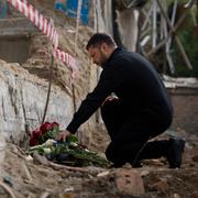 Zelenskyj placerar blommor vid en byggnad i Kyiv som attackerades av Ryssland med robotar, 19 juni. 