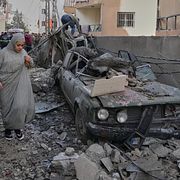 En kvinna går förbi en bil som träffats av ett israeliskt luftangrepp i staden Sidon i Libanon.