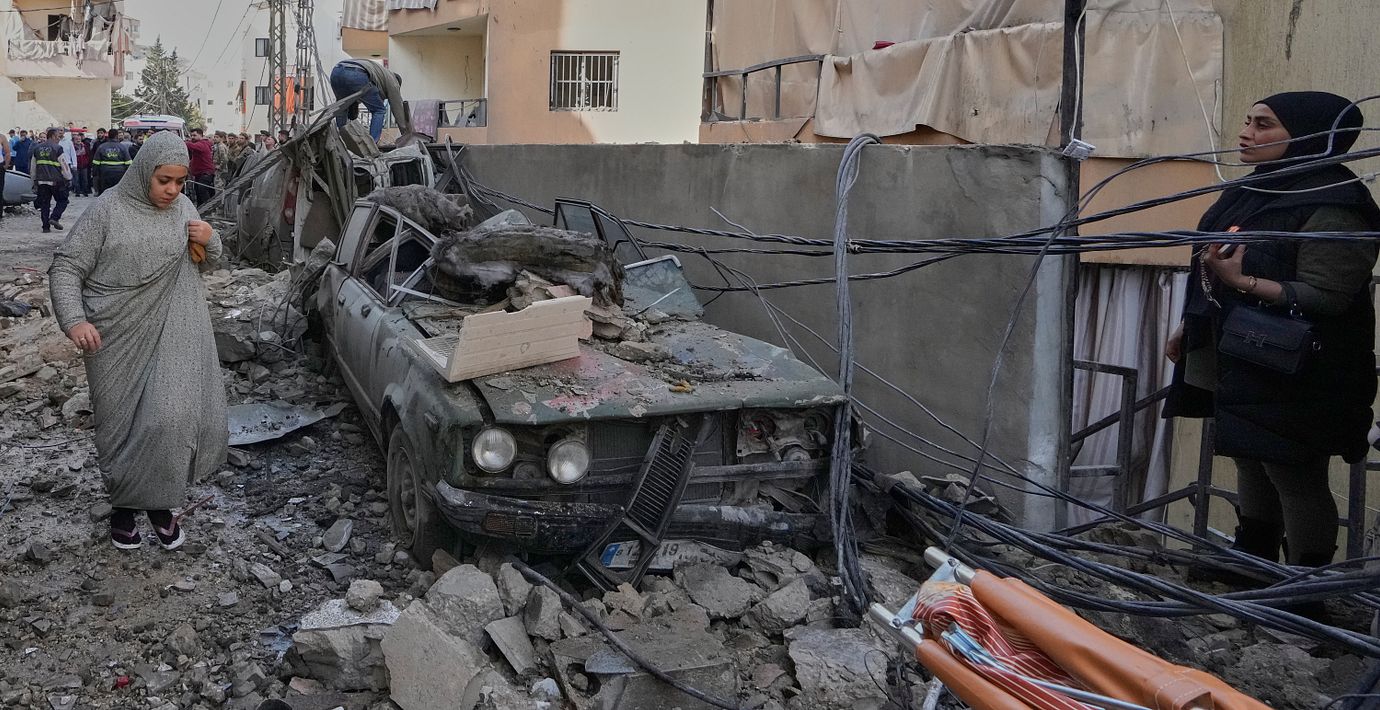En kvinna går förbi en bil som träffats av ett israeliskt luftangrepp i staden Sidon i Libanon.