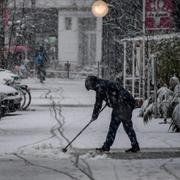En kvinna sopar bort snö i Hamburg. 