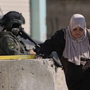 En palestinsk kvinna och israeliska soldater i Tulkarem på den ockuperade Västbanken den 17 december 2025. 