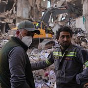 En räddningsarbetare från det libanesiska civilförsvaret, till höger, står med en boende vid en byggnad som förstörts i en israelisk flygattack i centrala Beirut, den 9 april 2026.