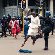 En polisman i Harare sparkar en demonstrant.