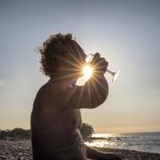 Man dricker vin på stranden i solnedgången på Öland, Horns udde.