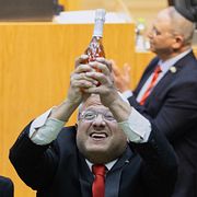 Itamar Ben-Gvir, minister för inrikes säkerhet, jublar med en flaska bubbel efter att lagen antagits. Ben-Gvir är dömd flera gånger, bland annat för att ha stöttat judiska terrororganisationer.  Till höger en bild från ockuperade Västbanken.