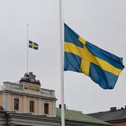 Flaggor på halvstång utanför UD / En person tänder ett ljus utanför Risbergska skolan.