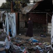 En kvinna står mitt i ett tältläger som attackerades i Deir al-Balah. 