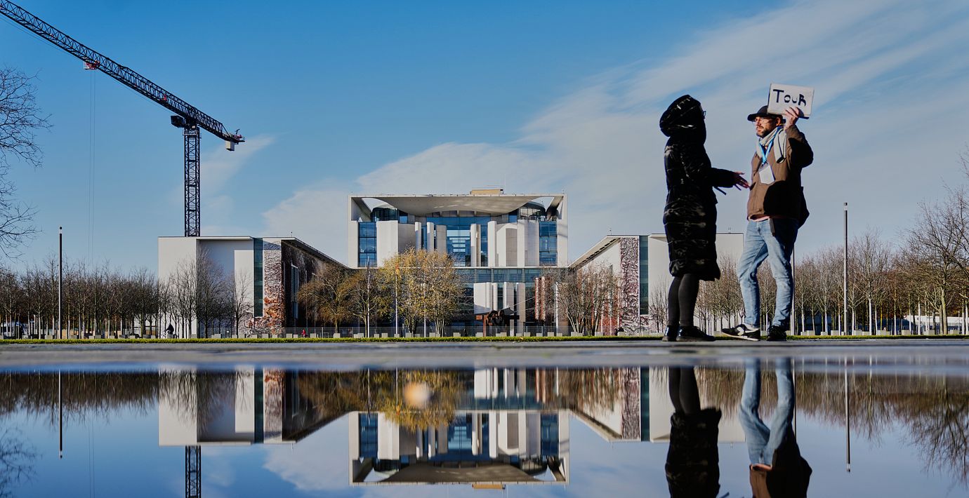 Illustrationsbild. En tourguide utanför förbundskanslerns kansli i Berlin.