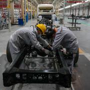 Workers assemble a chassis frame of a minibus at a Tenglong Automobile Co. manufacturing factory during a media-organized tour in Xiangyang in central China's Hubei Province on May 10, 2023.