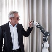 ABB:s vd Björn Rosengren skakar hand med en av bolagets robotar.