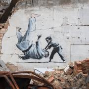  En kvinna tar en bild av ett konstverk på en förstörd byggnad i Borodyanka, i Kyivregionen, Ukraina, söndagen den 13 november 2022. Konstverket ska ha gjorts av den brittiske gatukonstnären Banksy. En annan väggmålning i Borodyanka bekräftades vara gjord av konstnären. 