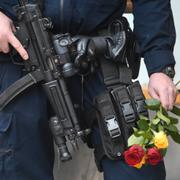 Beväpnad polis i Stockholm med blommor i handen.