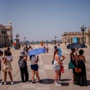 Människor skyddar sig mot solen med paraplyer i Spanien. 