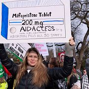 En aborträttsaktivist håller upp en skylt föreställande en burk mifepriston under en protest utanför högsta domstolen 2024.