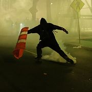 En demonstrant sparkar undan en tårgasgranat under nattens protester.