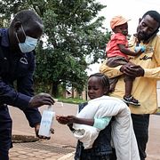 En flicka spritar händerna utanför sjukhus i Kampala.
