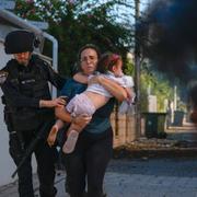 Israeliska poliser som hjälper en kvinna och hennes barn att fly raketeld i israeliska Ashkelon. 
