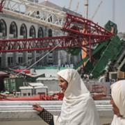 Muslimska pilgrimer vandrar förbi den välta kranen