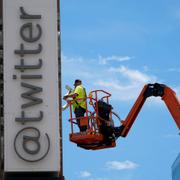 En byggnadsarbetare plockar ner skylten på Twitters huvudkontor efter att Elon Musk bytt namn på företaget till X. 