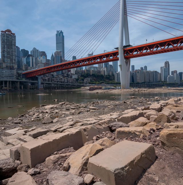 Rocks are exposed on the dry riverbed of the Jialing River in southwestern China's Chongqing Municipality, Friday, Aug. 19, 2022. Ships crept down the middle of the Yangtze on Friday after the driest summer in six decades left one of the mightiest rivers shrunk to barely half its normal width and set off a scramble to contain damage to a weak economy in a politically sensitive year. Mark Schiefelbein / AP
