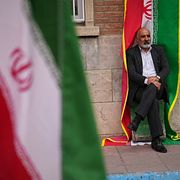 En man sitter framför en iransk flagga under en regerinststödd protest mot USA:s och Israels attacker i Teheran.