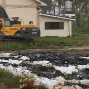 En man försöker identifiera anhöriga i massgrav i Tacloban.