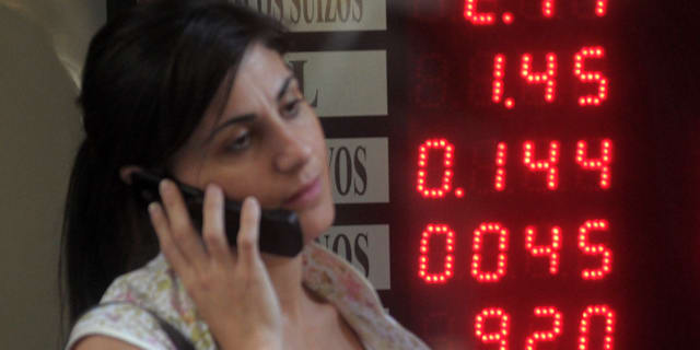Kvinna framför tavla med växlingskurser i Buenos Aires. Illustrationsbild. Daniel Luna / AP