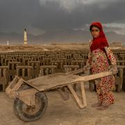 En nio år gammal flicka arbetar på en fabrik i Afghanistan.