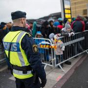 En polis övervakar kön av ankommande flyktingar i snålblåsten vid Hyllie station utanför Malmö en torsdagseftermiddagen 2015.